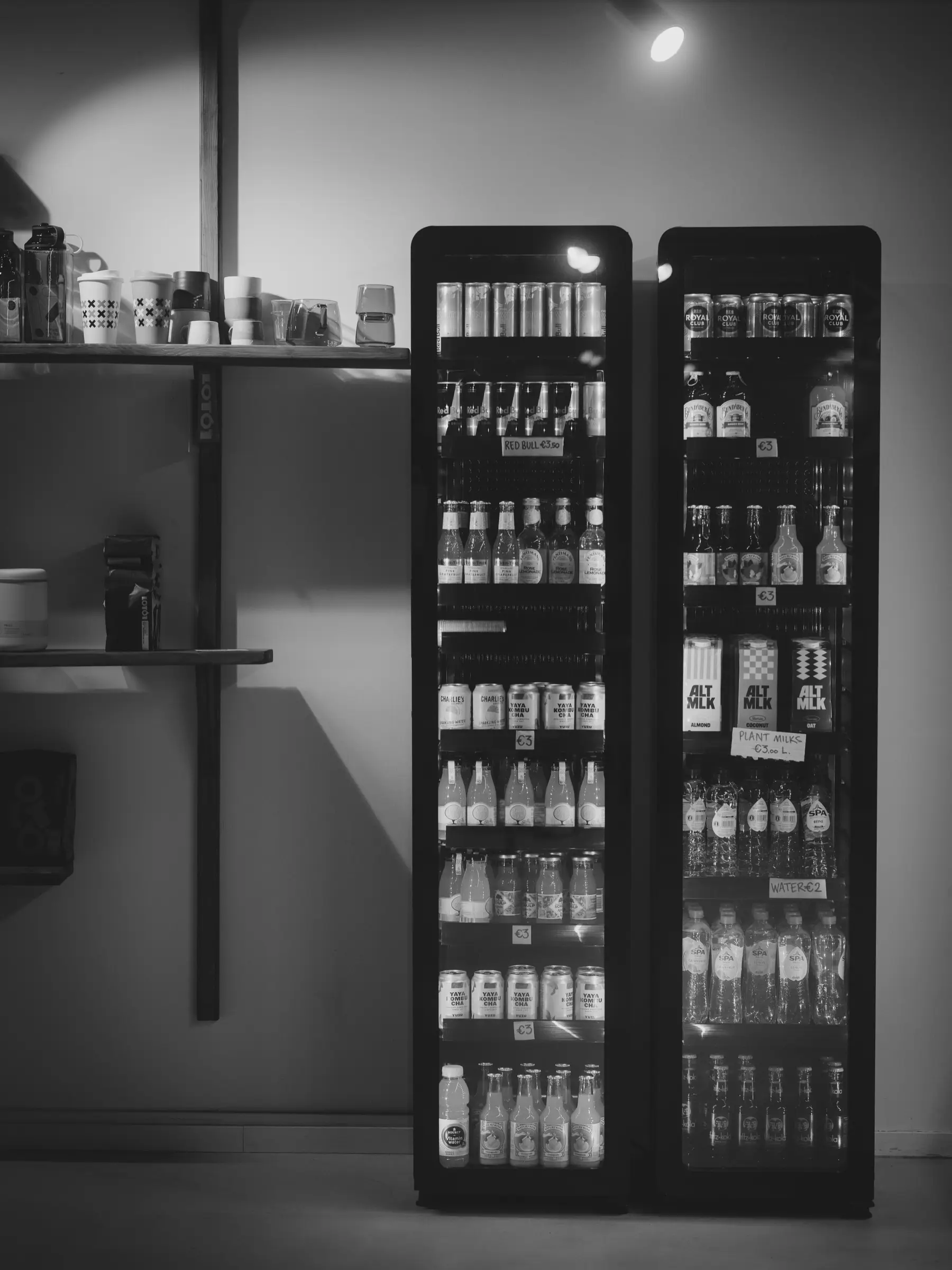 Two glass-door drink coolers stocked with cans and bottles, with price cards on the shelves