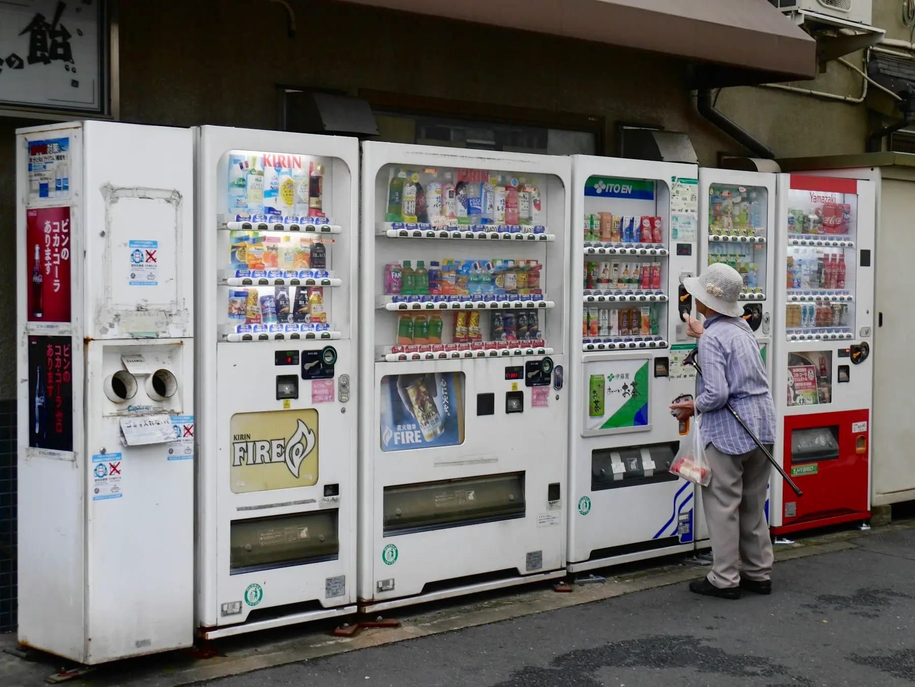 A row of drink vending machines on a sidewalk