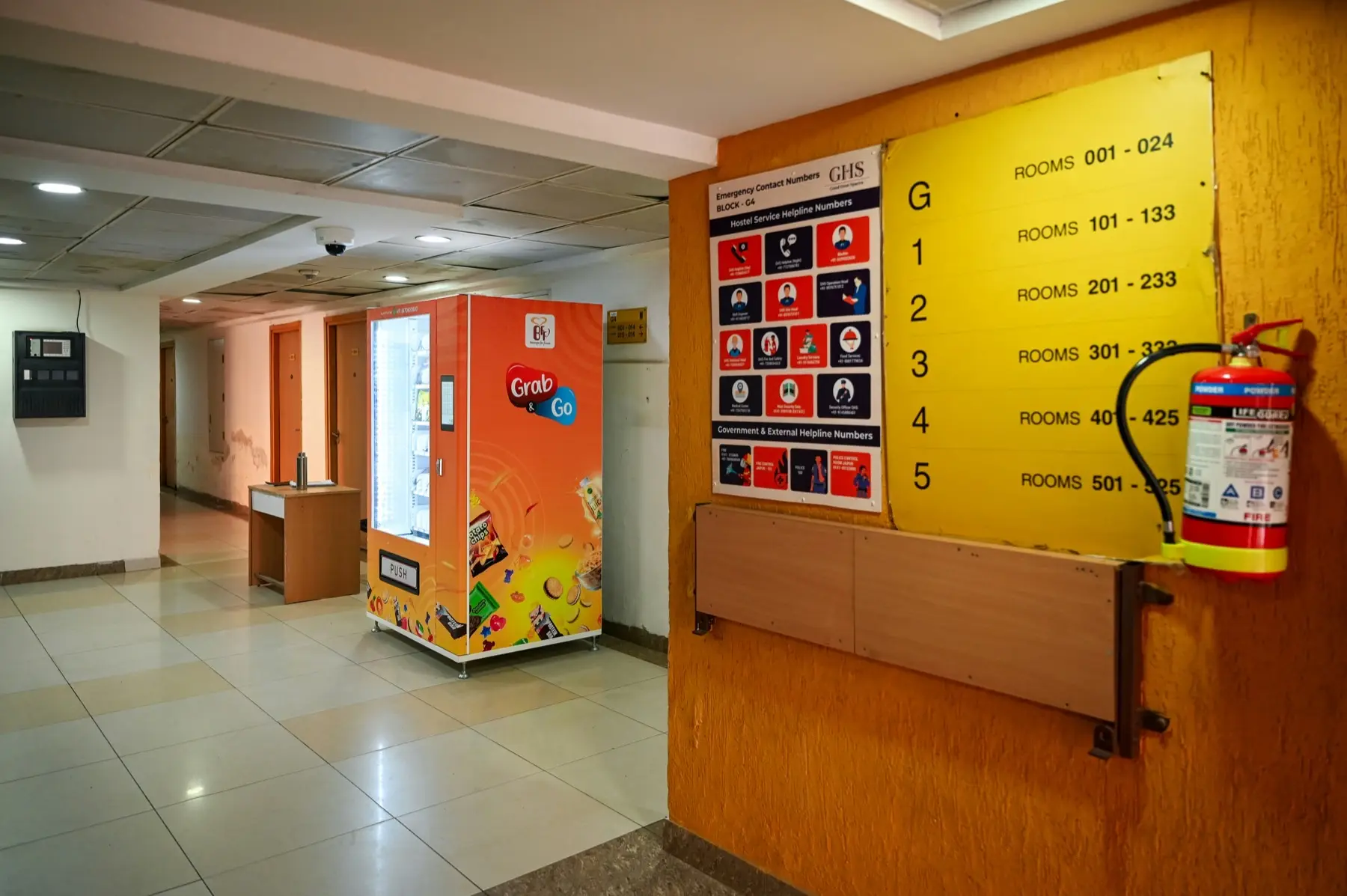 A snack vending machine in a university building hallway next to a floor directory